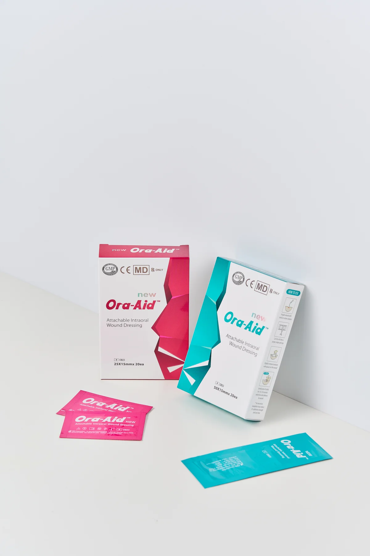Ora-Aid pink and teal product boxes with individual wound dressing sachets